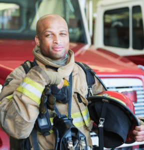 African American male firefighter standing in front of firetruck